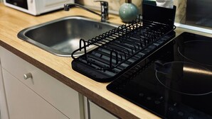 A kitchen with a stainless steel sink, a black dish rack, a microwave, and a stove. - Mini - Small but cozy! (Brignoles)