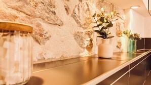 A modern interior with a stone wall, a long counter, and two potted plants. - Dubonnet - Coeur de ville (Brignoles)