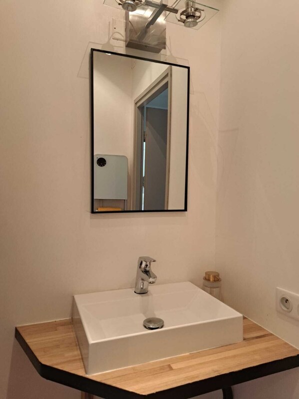 A bathroom with a white sink, a mirror, and a wooden countertop.
