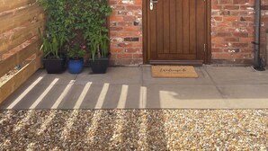 A brick building with a wooden door, a sign reading "The Piggy," and a welcome mat. - THE PIGGERY CHESHIRE. The perfect place to get away from it all (Smallwood)
