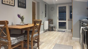 A dining area with a wooden table and chairs, a vase with flowers, and framed botanical prints on the wall. - THE PIGGERY CHESHIRE. The perfect place to get away from it all (Smallwood)
