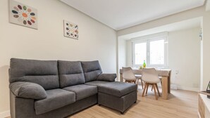 Una sala de estar moderna con un sofá modular gris, una mesa de comedor con sillas y obras de arte en las paredes.