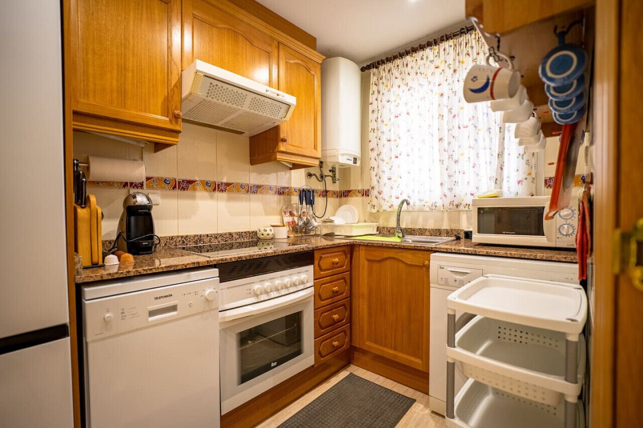 A compact kitchen with wooden cabinets, a microwave, a dishwasher, and a sink.