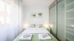 A hotel room with a bed, two nightstands, a green towel, and two wall-mounted pictures. - Family-Friendly Stay near Madrid (San Sebastián de los Reyes)