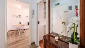 A hotel room with a wooden floor, a dining area with a white table and chairs, a mirror with a white orchid, and a door labeled "SALON". - Family-Friendly Stay near Madrid (San Sebastián de los Reyes)