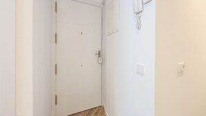 A white door with a handle, a wall-mounted telephone, and a light switch. - Urban Tranquility in Madrid - Ideal for Couples (Madrid)