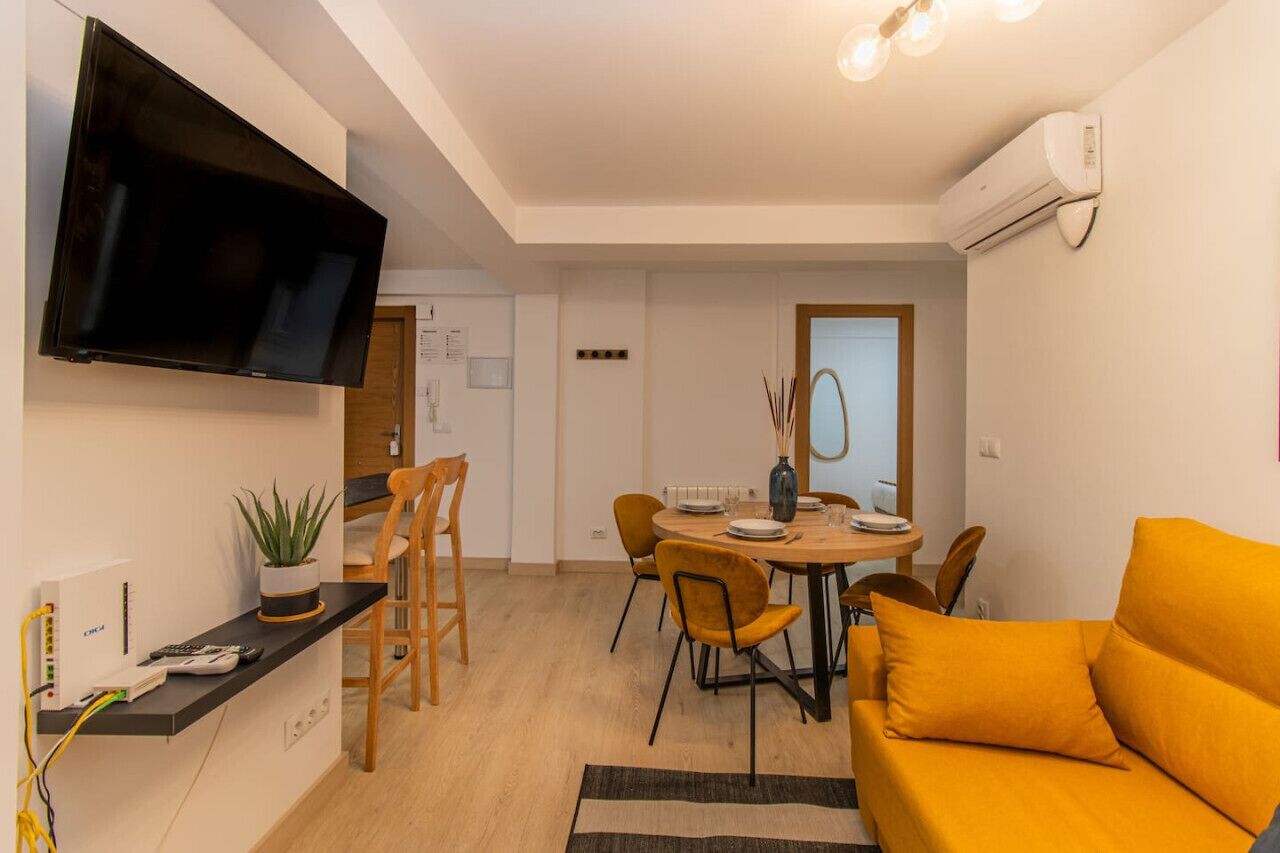 Un salon moderne doté d’un téléviseur à écran plat, d’un canapé et d’un coin repas avec des chaises et une table.