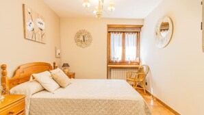 A bedroom with a bed, wooden headboard, bedside table, lamp, and a window with curtains. - Rustic House in the Pyrenees, ideal for families (Senegüé)