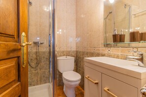 A bathroom with a toilet, shower, and vanity with a mirror. - Rustic House in the Pyrenees, ideal for families (Senegüé)