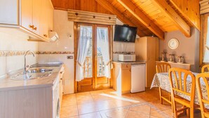 A compact kitchen with a sink, microwave, and wooden cabinets. - Rustic House in the Pyrenees, ideal for families (Senegüé)