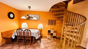 A dining area with a table and chairs, a clock on the wall, a decorative shelf, and a wooden spiral staircase. - Rural Duplex in the Pyrenees - Garden and Parking (Senegüé)