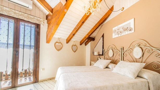 A bedroom with two beds, wooden beams, a chandelier, and a large window with a view. - Rural Duplex in the Pyrenees - Garden and Parking (Senegüé)