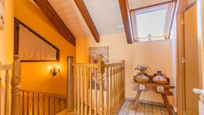 A wooden staircase with a railing, a wall-mounted light fixture, and a small table with vases. - Rural Duplex in the Pyrenees - Garden and Parking (Senegüé)