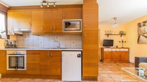 A compact kitchen with wooden cabinets, a built-in microwave, a small refrigerator, and a tiled backsplash. - Rural Duplex in the Pyrenees - Garden and Parking (Senegüé)