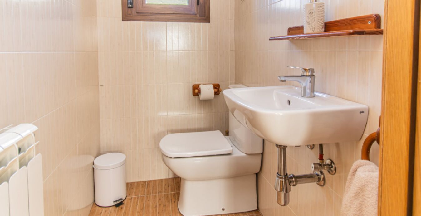 A small bathroom with a toilet, sink, and a small trash bin.