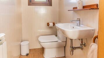 A small bathroom with a toilet, sink, and a small trash bin.