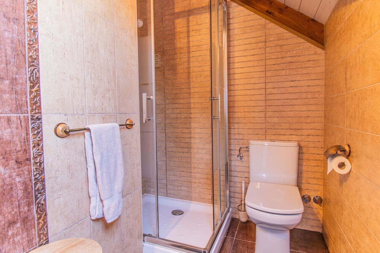 Un baño con cabina de ducha de vidrio, inodoro y barra para toallas.