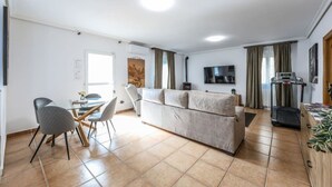 En moderne stue med sofa, spisebord, stole, fjernsyn og løbebånd.