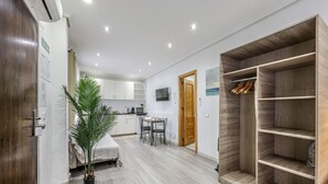 A modern hotel room with a wooden wardrobe, a dining area with a table and chairs, a kitchen area, and a potted plant. - Classy Studio close to Retiro Park, Madrid (Madrid)