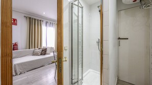 A modern bathroom with a glass shower enclosure, a white bathtub, and a wooden door frame. - Classy Studio close to Retiro Park, Madrid (Madrid)