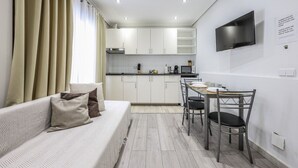 A compact living space with a kitchenette, a dining area, and a sofa with cushions. - Classy Studio close to Retiro Park, Madrid (Madrid)