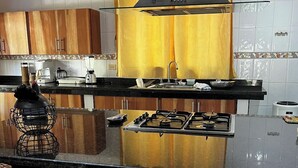 Een keuken met een centraal eiland, houten kastjes, een gasfornuis en een geel gordijn.