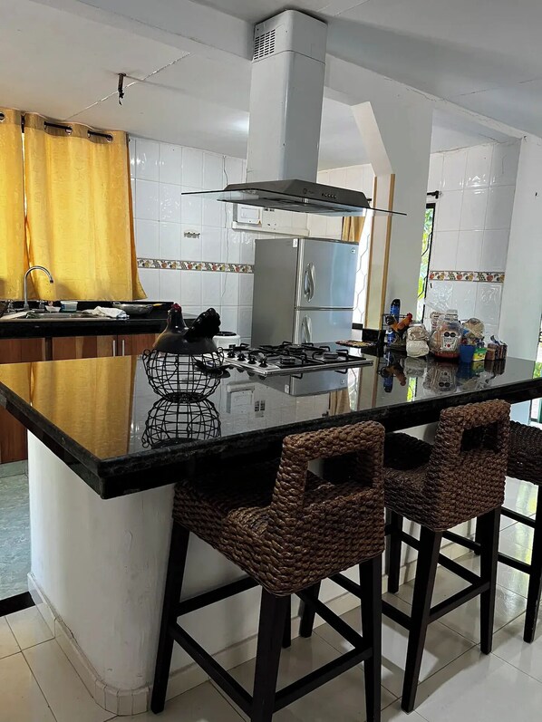 A modern kitchen with a central island, stainless steel appliances, and a large window. - Casa finca Santiago Tolú
(Tolu)