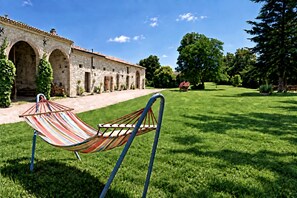 A hammock in a grassy area with a stone building in the background.