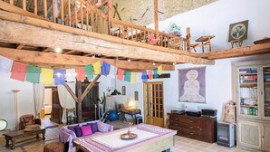Een rustiek interieur met een houten trap, gebedsvlaggen, een meditatiebeeld en traditioneel meubilair.