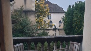 A patio with wooden chairs and a barrel, surrounded by a stone balustrade and greenery. - L (Saint-Amand-Montrond)