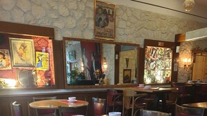 A restaurant interior with round tables, cushioned chairs, and a stone wall. - L (Saint-Amand-Montrond)
