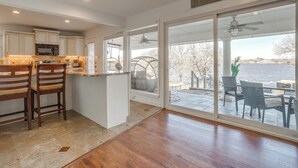 A kitchen with a large island, a dining area with a view of the water, and a sliding glass door leading to an outdoor patio.