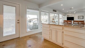 A spacious kitchen with a large island, white cabinetry, and a view to the outside.
