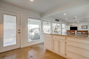 A spacious kitchen with a large island, white cabinetry, and a view to the outside.