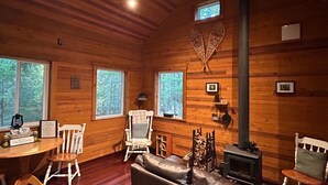 Un acogedor interior de cabaña con paredes de madera, una chimenea, un sofá de cuero y una zona de comedor.