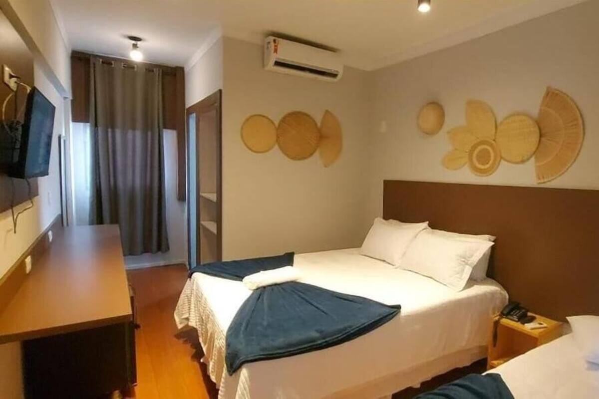 A hotel room with a bed, bedside table, and a TV.