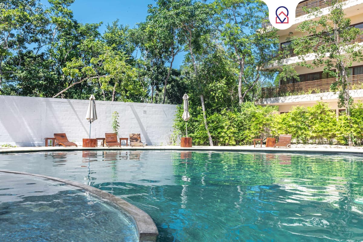 A swimming pool with lounge chairs and a white wall.