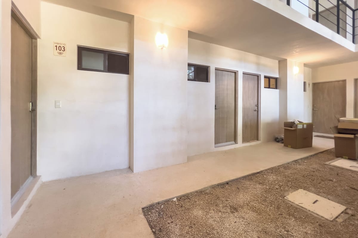 A hallway with three doors, a staircase, and a small trash bin.
