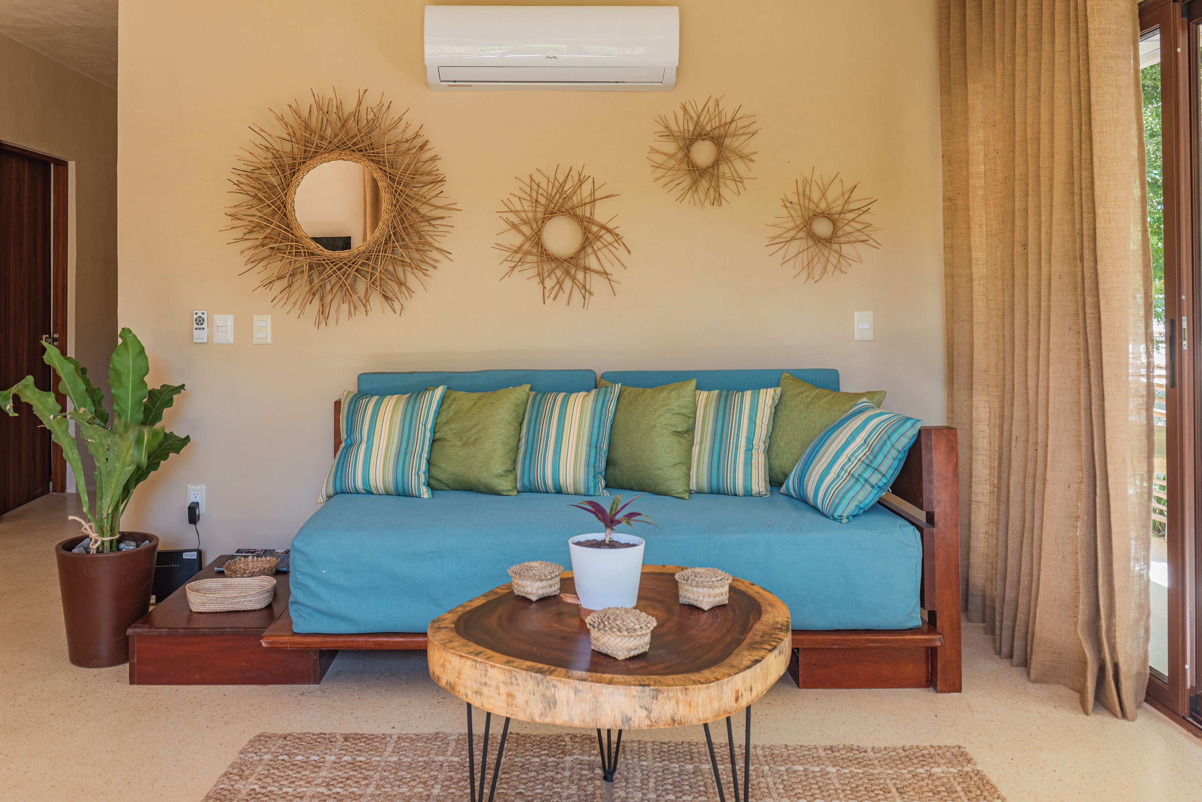 A living room with a blue sofa, decorative wall art, a potted plant, and a wooden coffee table.