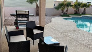 An outdoor patio area with wicker furniture, a grill, and a pool. - Havasu Pool Home with A/C Boat Garage + Toy Parking (Lake Havasu City)