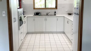 A compact kitchen with white cabinets, a built-in oven, a sink, and a window above the countertop. - Just Beachy, Port Victoria (Port Victoria)