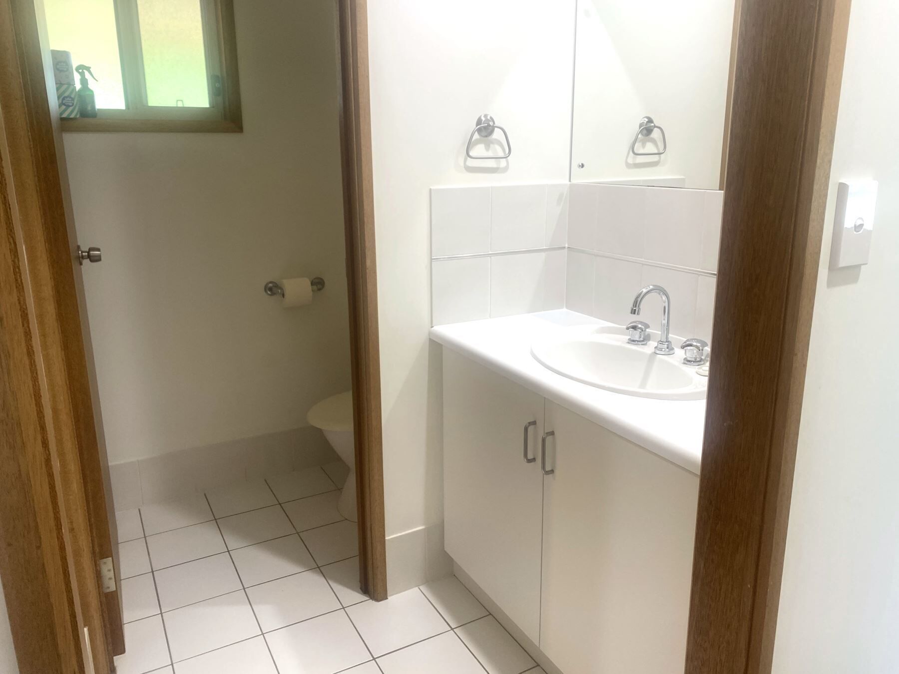 Un baño con lavamanos blanco, espejo y retrete.