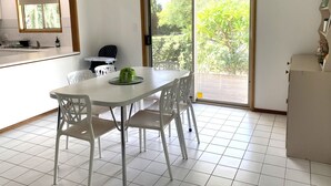 A dining area with a white table and chairs, a blue pendant light, a small indoor plant, and a sliding glass door leading to an outdoor patio. - Just Beachy, Port Victoria (Port Victoria)