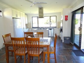 A modern kitchen with white cabinets, a dining table with chairs, a stove, and a dishwasher. - Ardy House, Ardrossan (Ardrossan)