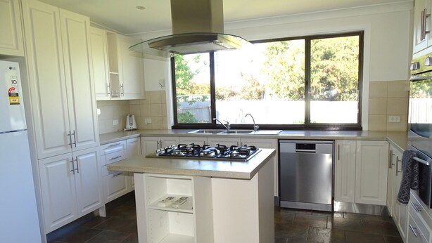 A modern kitchen with white cabinets, a gas stove, a dishwasher, and a large window providing natural light. - Ardy House, Ardrossan (Ardrossan)