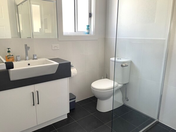 A modern bathroom with a white sink, mirror, and toilet.