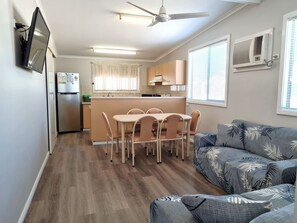 A compact living space with a kitchenette, dining area, and a sofa with a tropical print. - Reel Relaxation, Fisherman Bay (Fisherman Bay)