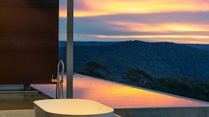 A modern outdoor bathroom with a view of a sunset over a forested hill. - Mountain Top Bilpin, Studio 1 Isyd (Bilpin)