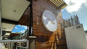 Ein Gebäude mit Holzfassade, einem Metallzaun und einem Schild mit der Aufschrift 'White Sands Playa del Carmen'.