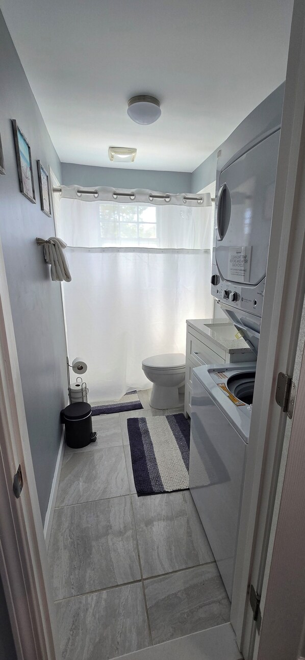 Ein kleines Badezimmer mit Toilette, Waschmaschine und kleinem Mülleimer.